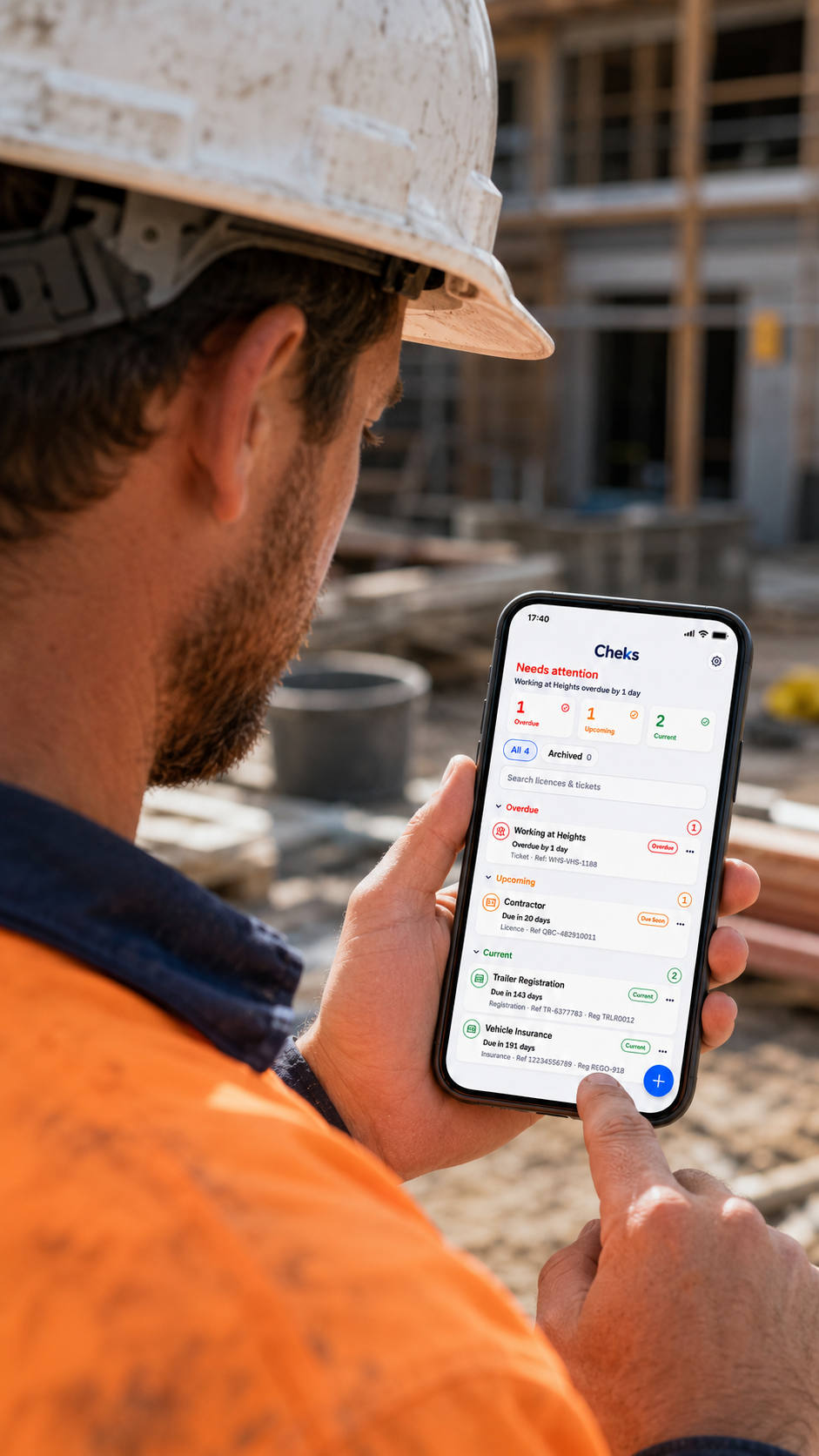 A tradie checking the Cheks renewal dashboard on a phone at a work site.